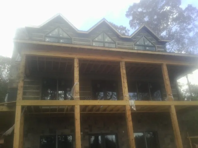 Dormers and porch framing on a large log home under construction — Roof Coating work by our crew in Berlin